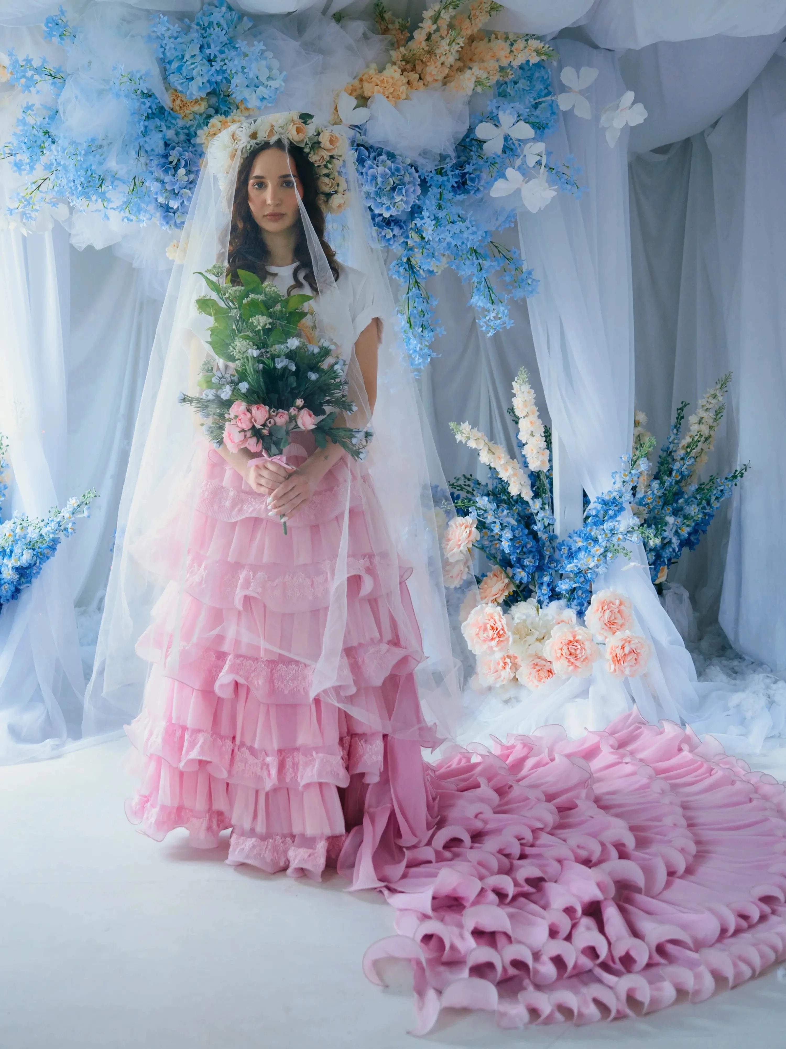 A woman wearing the dahlia pink ruffle skirt with floral decorations and a veil.