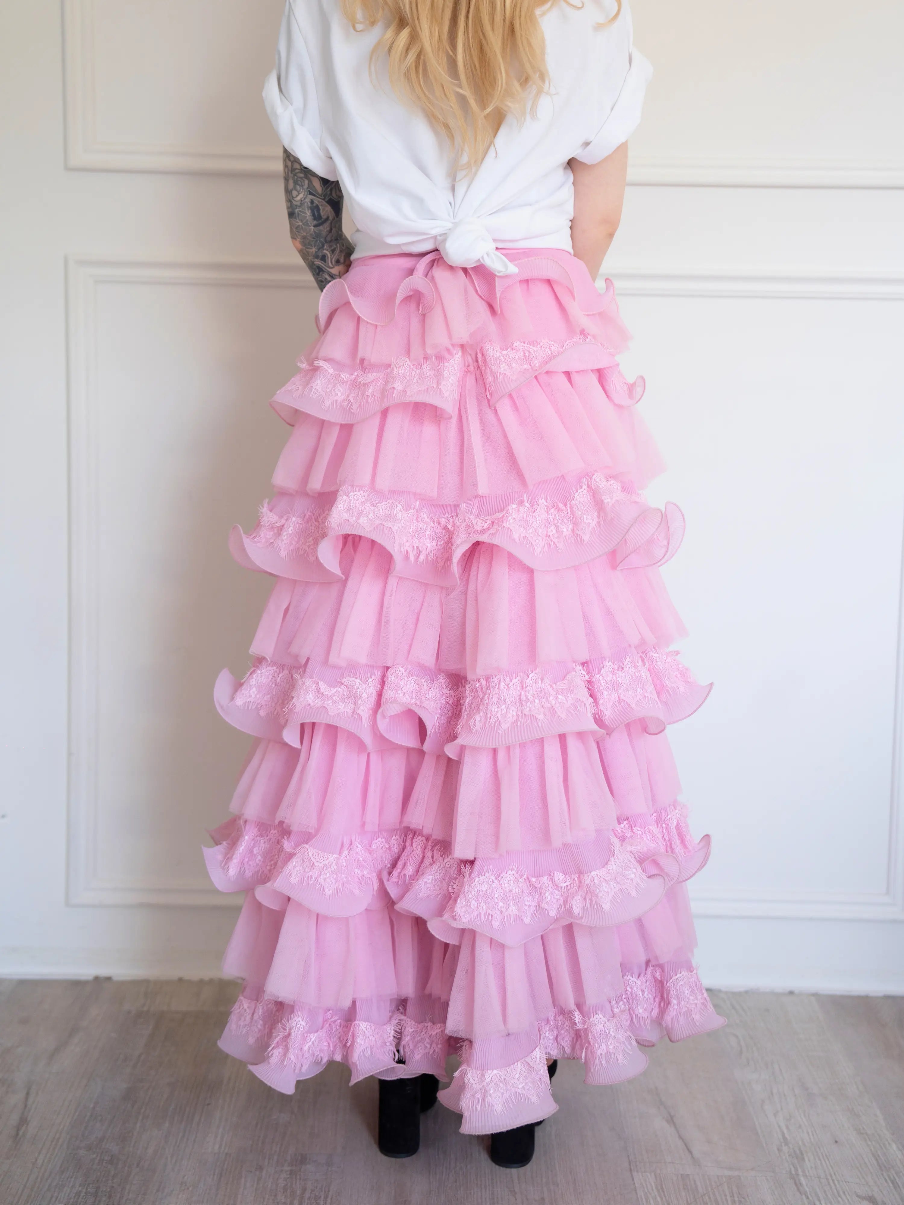 The Dahlia Ruffle Skirt | Fantasy Skirts rear view showing layered pink tulle and lace ruffles, styled with a knotted white tee for contrast.