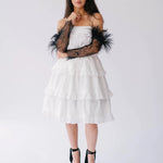 Full-body view of The Eleanor Black Feather Gloves styled with a white layered dress and black heels.