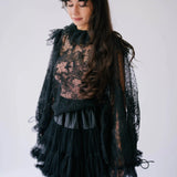Model wearing The Eleanor Midnight Black Lace Top with flowing sleeves and ruffled neckline, styled for a dark romantic look.