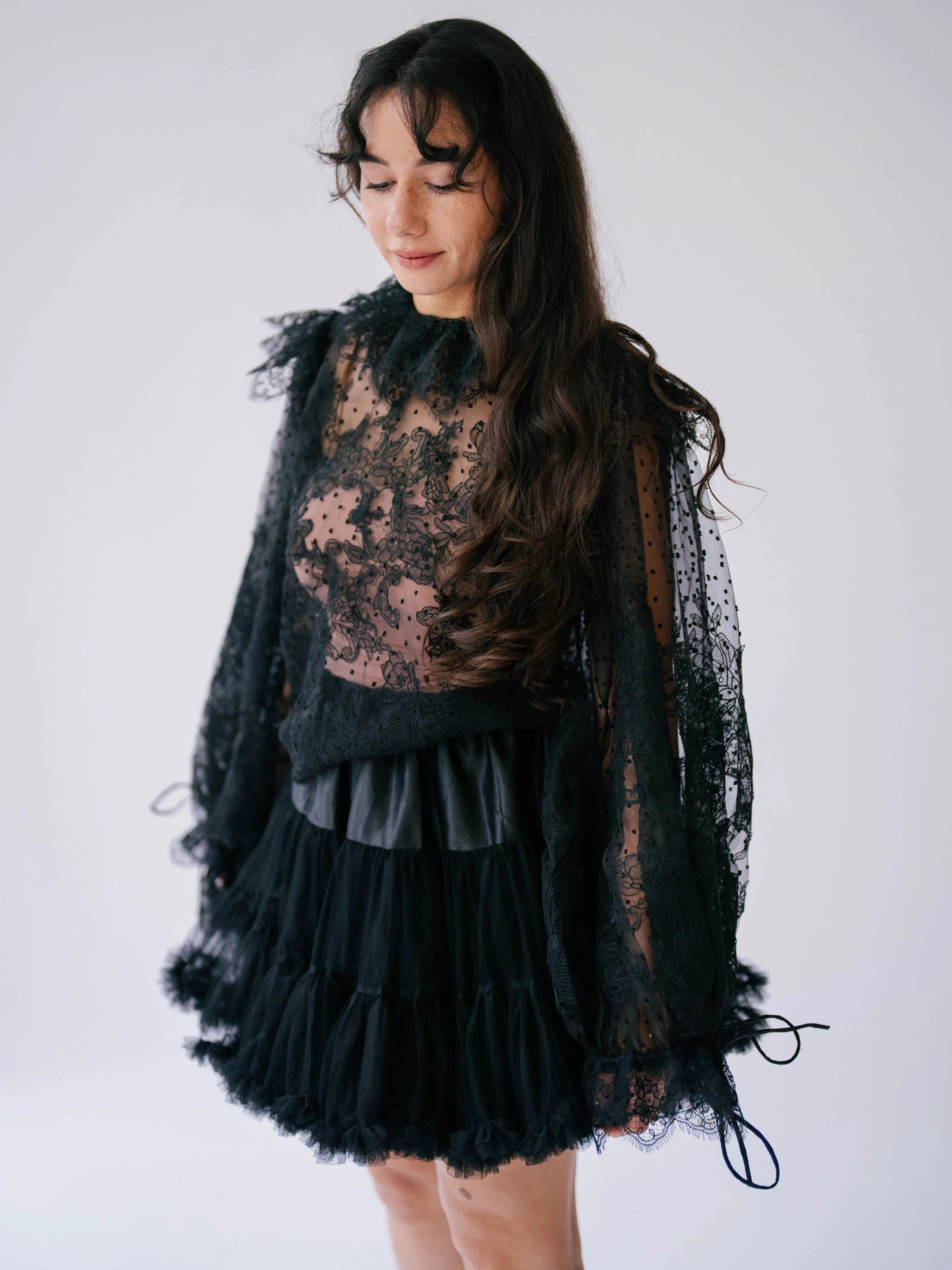 Model wearing The Eleanor Midnight Black Lace Top with flowing sleeves and ruffled neckline, styled for a dark romantic look.