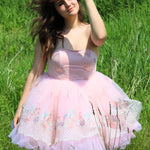 A woman wearing a pink tutu dress standing in a grassy field.