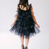 A second back view of a woman wearing a black puff dress in black platform heels.