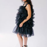 Side view of a woman wearing a black puff dress in black platform heels.