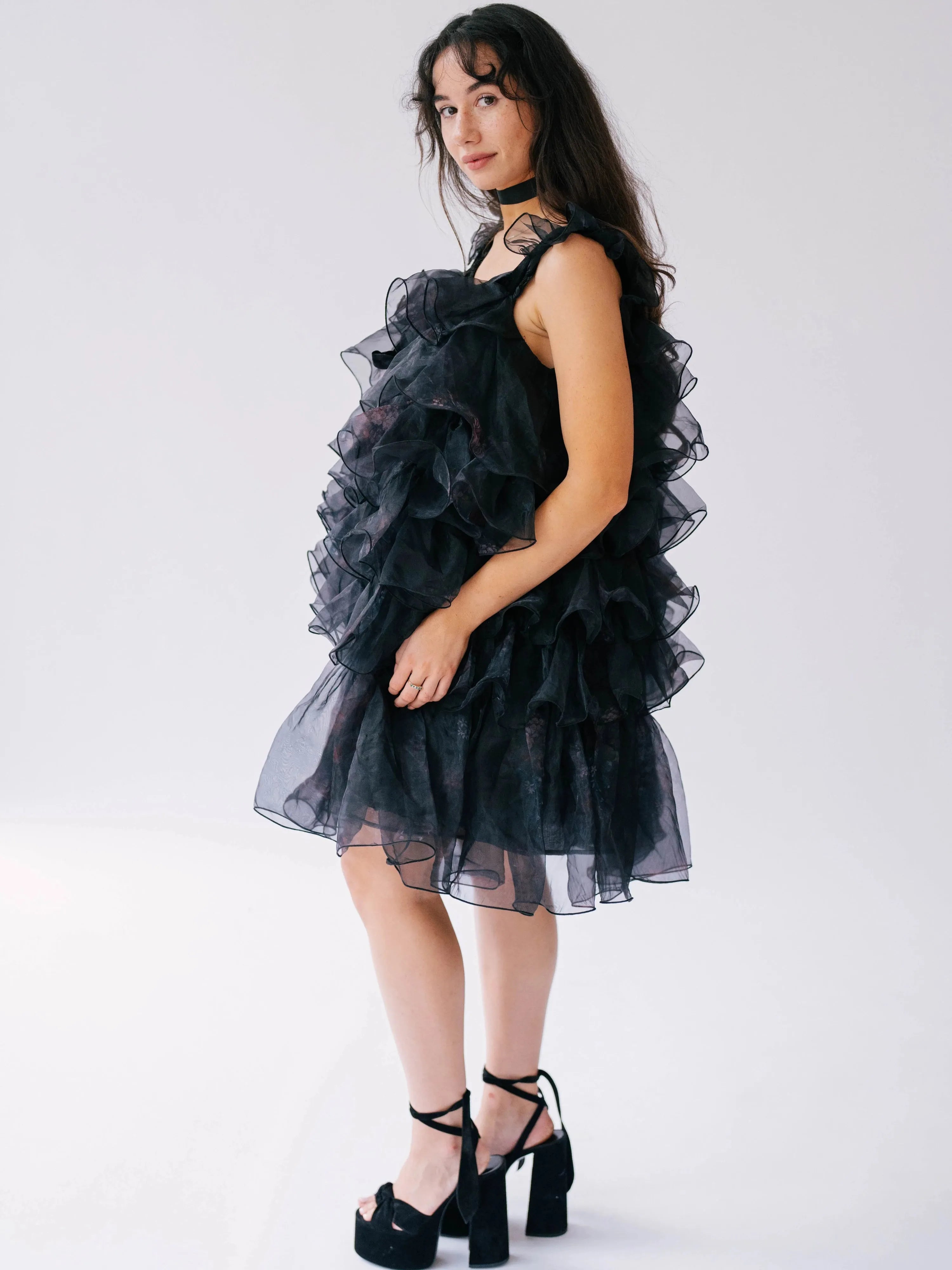 Side view of a woman wearing a black puff dress in black platform heels.