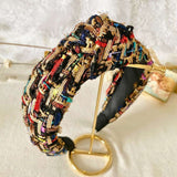 Colorful tweed headband with intricate patterns sitting on a white table.
