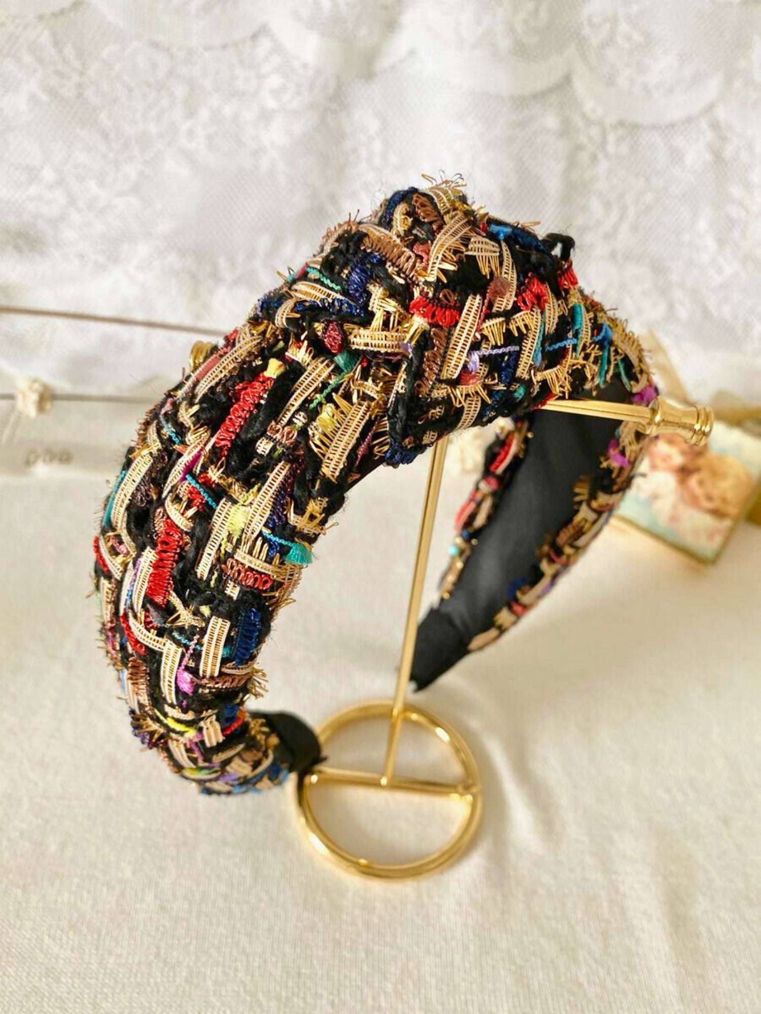 Colorful tweed headband with intricate patterns sitting on a white table.