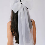 Close-up of a white bridal hair bow in a woman's hair.
