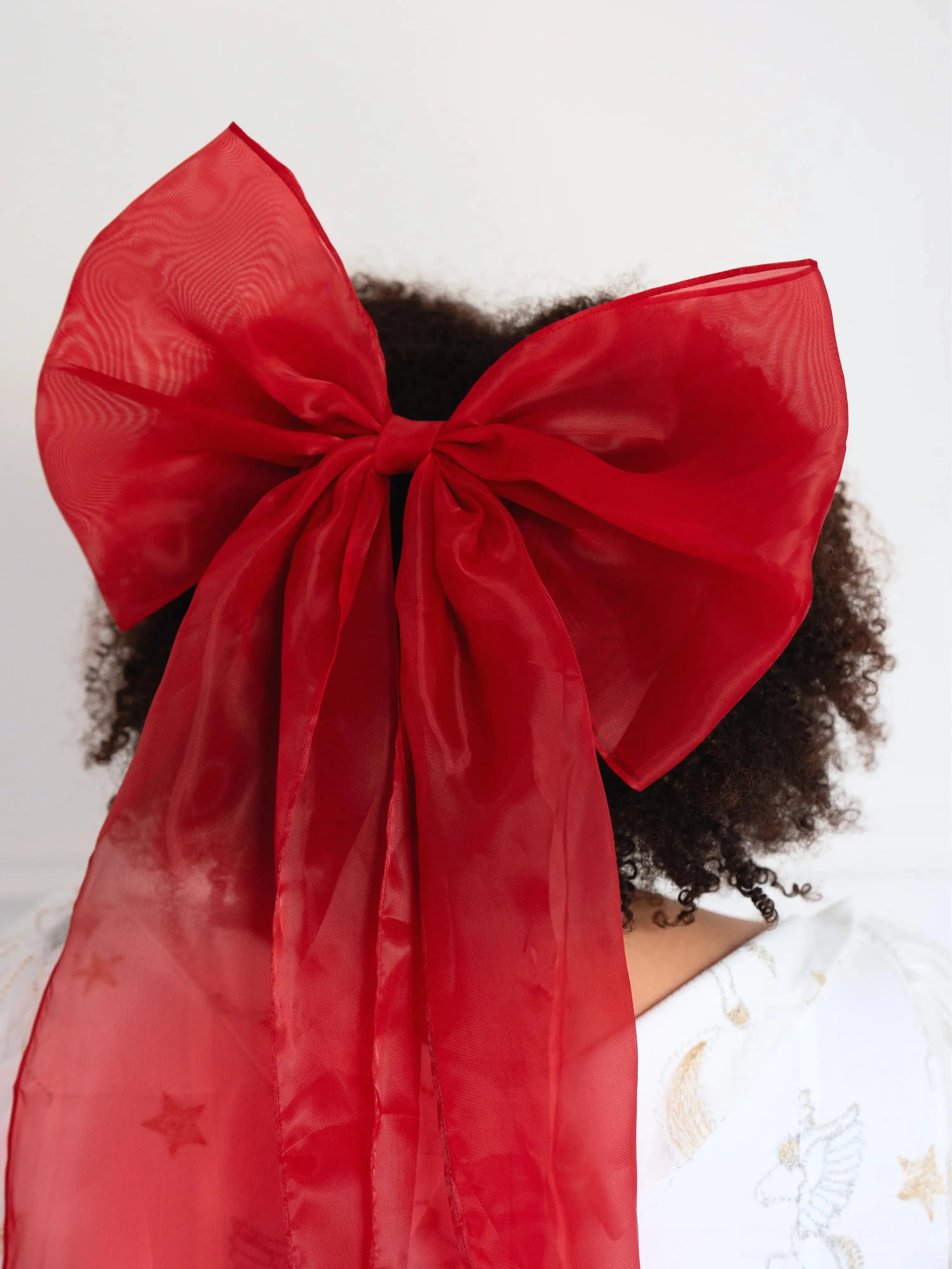 Close-up view of the holiday red grand hair bow in a woman's hair.