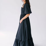 A woman wearing a black corset gown against a white background.