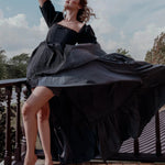 The Josephine Renaissance Gown in flowing black taffeta fabric with puff sleeves and corset bodice, captured mid-twirl on a balcony. Gothic fairytale style.