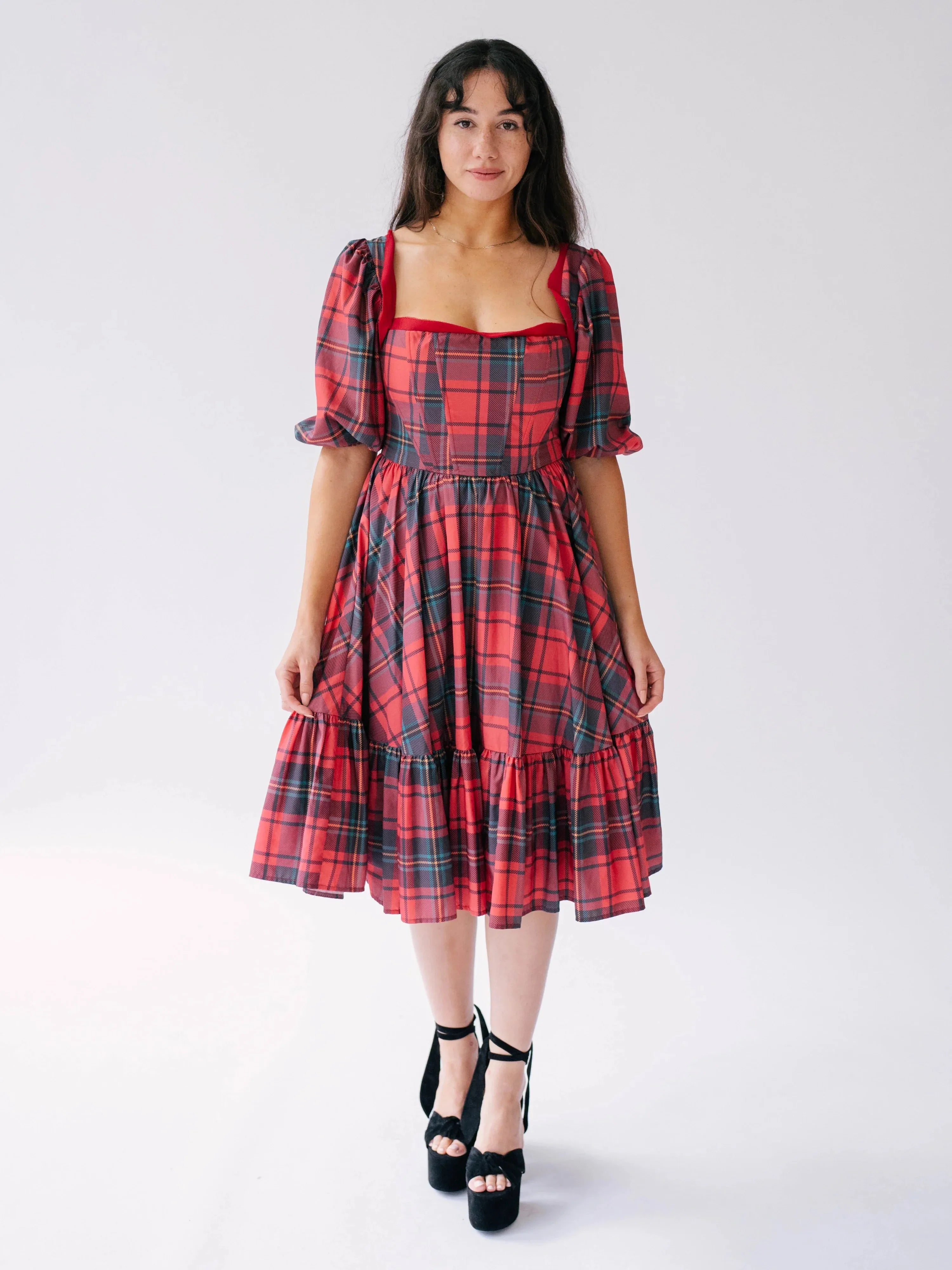 Full front view of a woman wearing a red tartan plaid dress on a white background.