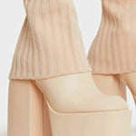Nude-colored knee high platform boots with chunky heels and ribbed pants legs visible above them.