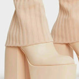 Nude-colored knee high platform boots with chunky heels and ribbed pants legs visible above them.