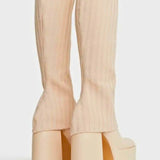 Cream-colored knee high platform boots with chunky heels and ribbed fabric texture.