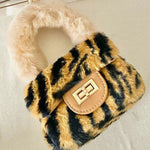 The Leopard Faux Fur Micro Purse features a bold leopard print design with a plush faux fur handle. It's shown on a plain table.