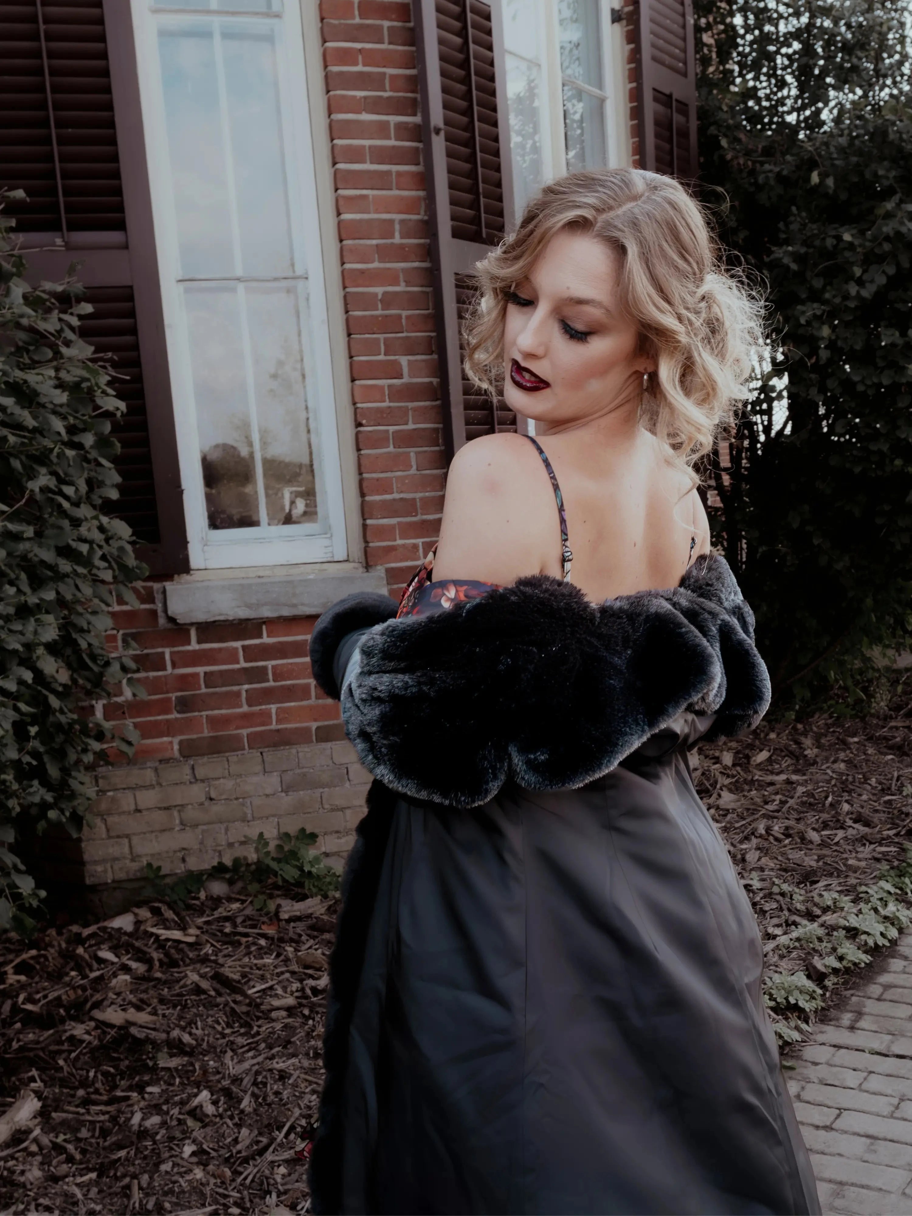 Back view of a woman in the Stained Rose Lilith Coat standing in front of a brick building.
