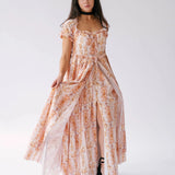 The twilight bloom meadow gown, is a cotton gown displayed with a front slit and puff sleeves, styled with platform heels for a modern romantic outfit.