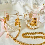 Clear mini bucket bags with gold chains and pearl accents on a white lace background