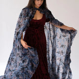 The High Priestess Victorian Cloak draped over a red dress, highlighting the sheer purple floral fabric and elegant Victorian silhouette.