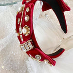 The Little Bit of Blair Red Velvet Headband showcases intricate gold embellishments and sparkling crystals on plush velvet.
