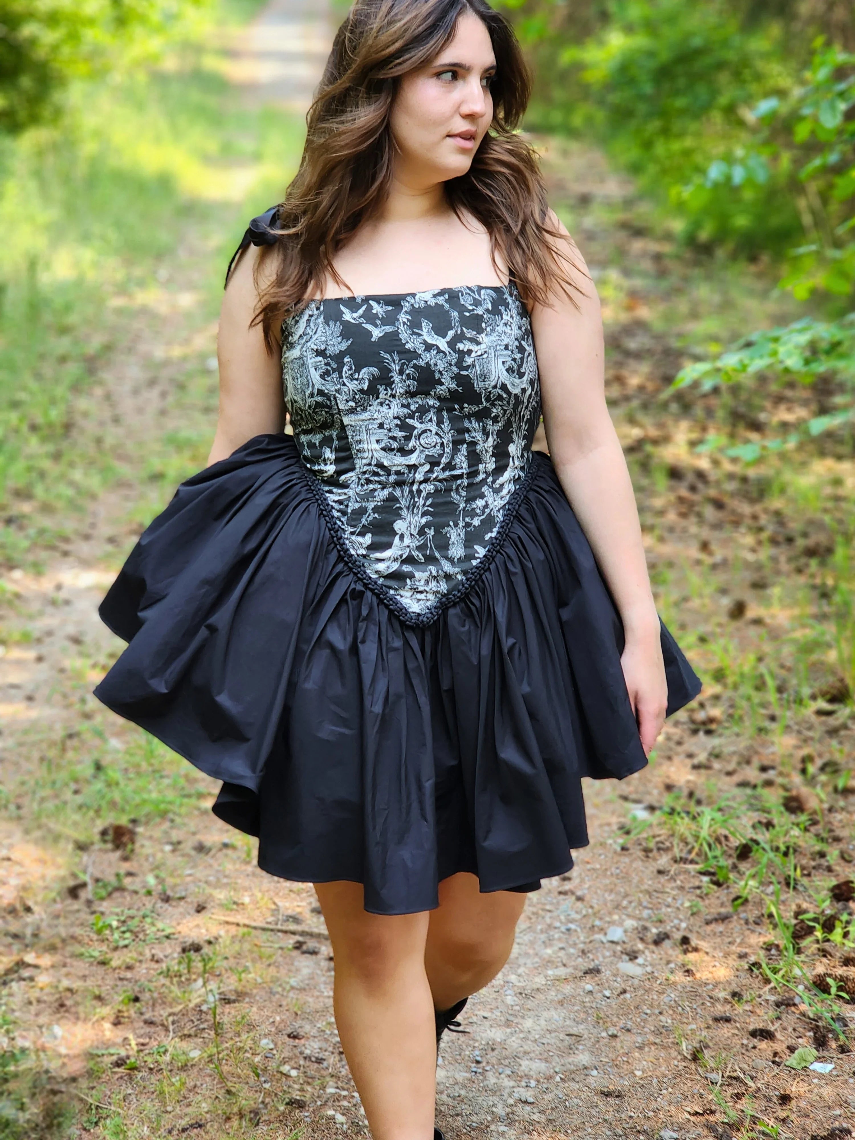 Woman in Rhiannon Corset Dress walking along a scenic path in a forest. A perfect fairytale setting.