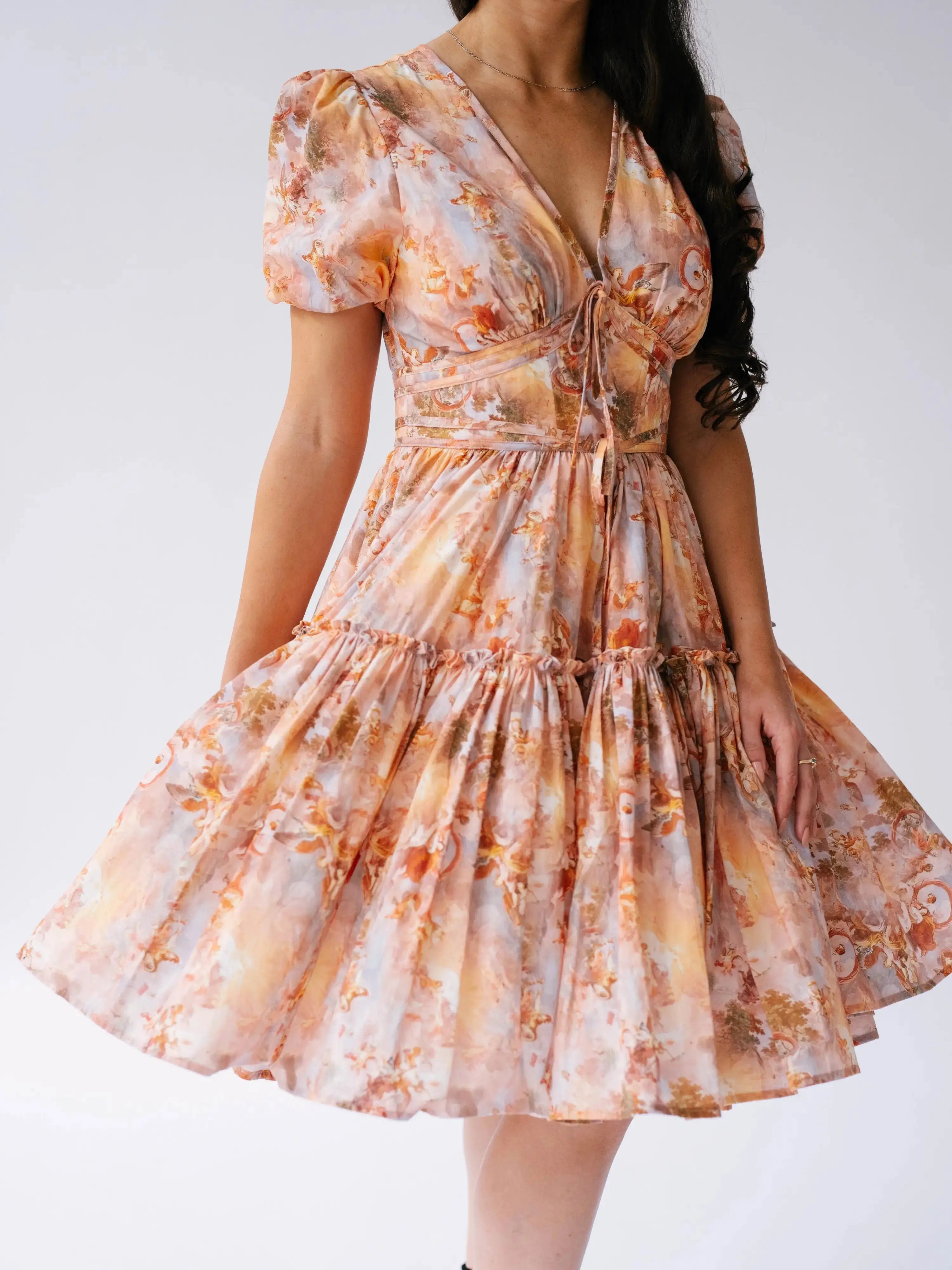 Close-up of Ode To Jove Grace Day Dress showing detailed fresco print, ruched bodice, and swishable tiered skirt. Feminine and structured design.