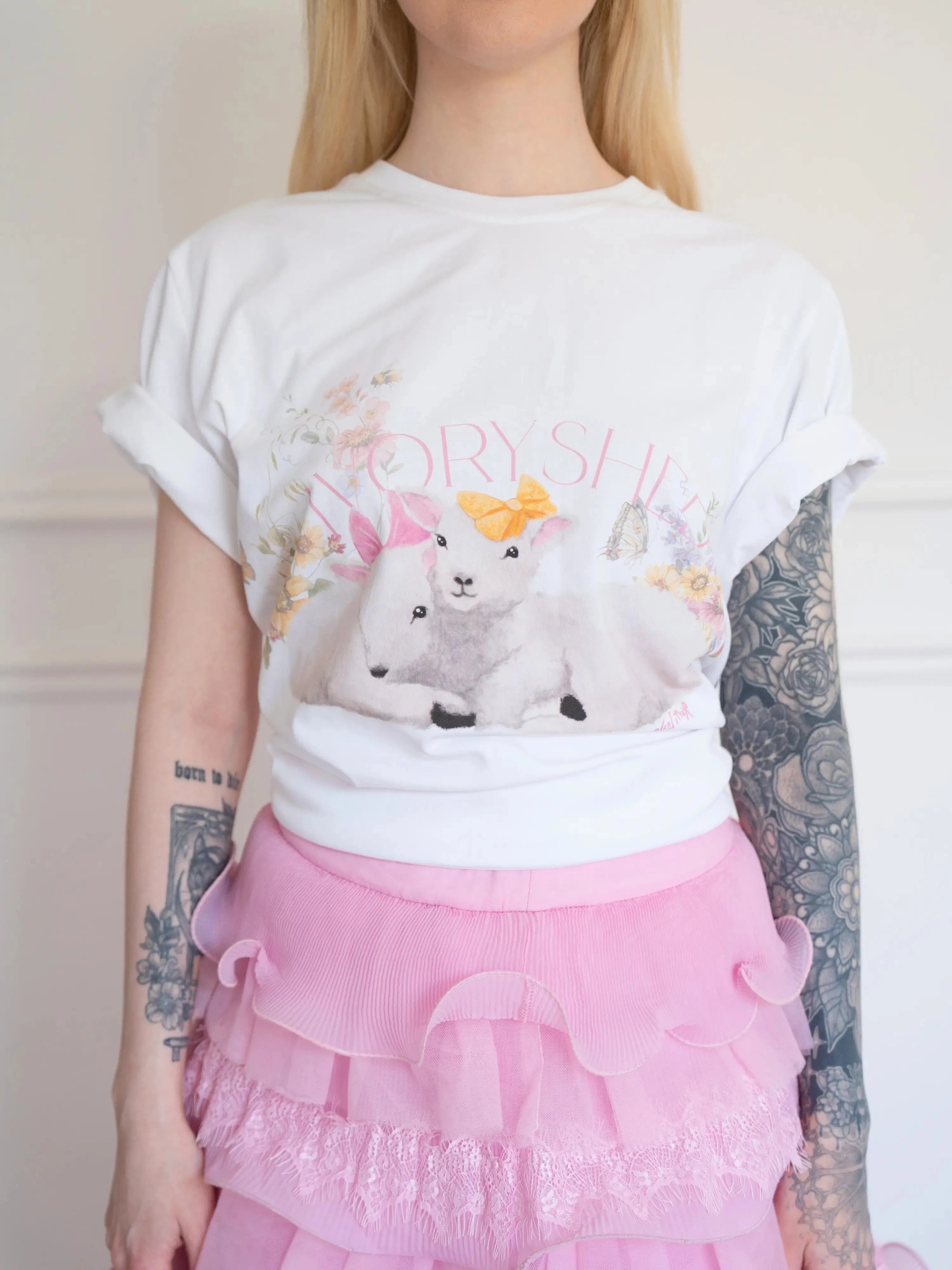 Front view of The Little Lamb Tee tucked into a pink layered lace skirt, featuring charming lambs and floral artwork for a dreamy look.