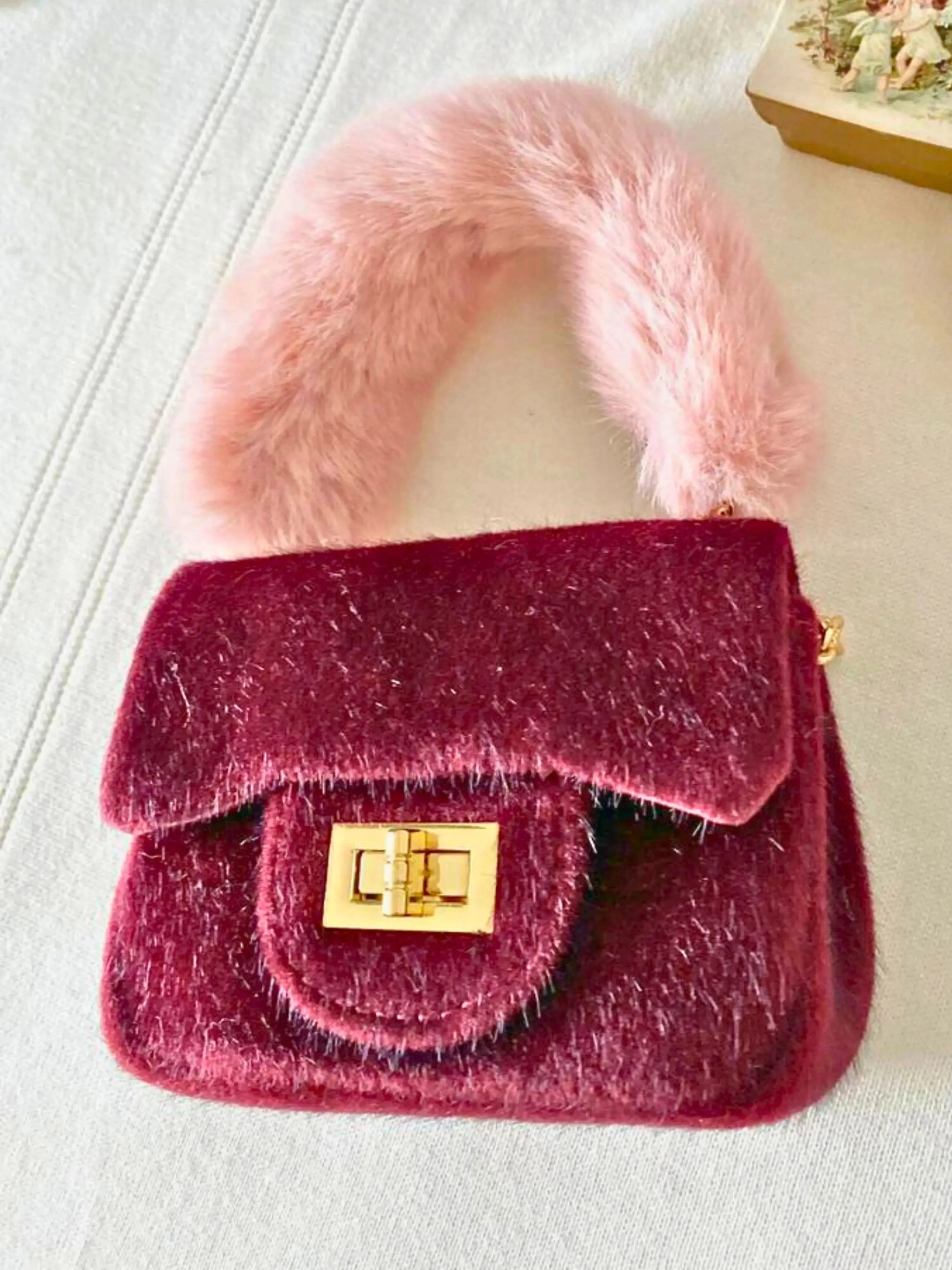 Micro-sized The Petit Agneau Tiny Purse in wine with soft faux fur handle and gold hardware, ideal for stylish minimal accessories.
