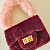 Wine-colored The Petit Agneau Tiny Purse featuring a plush faux fur handle and gold turn-lock clasp, perfect for compact luxury fashion.