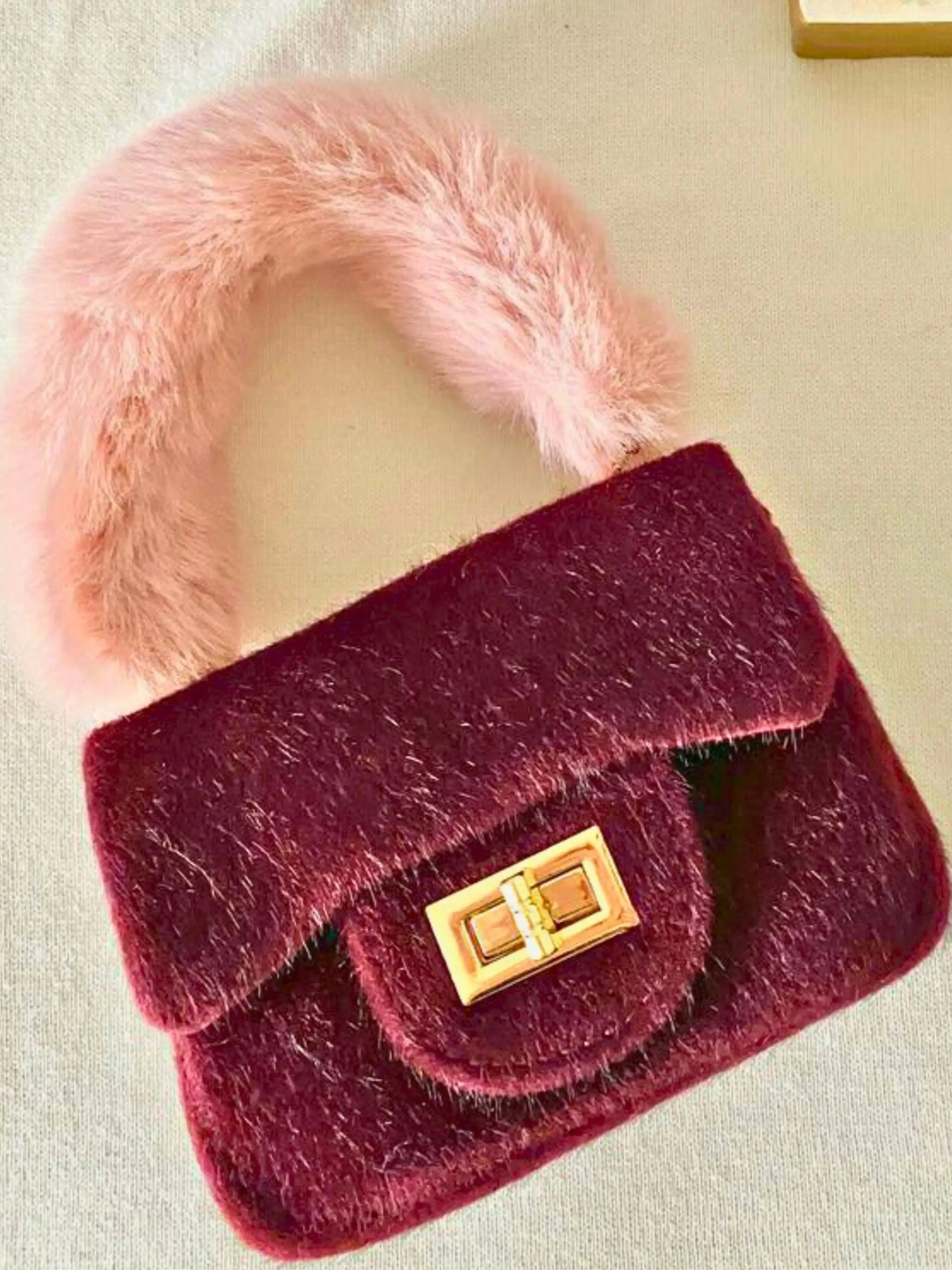 Wine-colored The Petit Agneau Tiny Purse featuring a plush faux fur handle and gold turn-lock clasp, perfect for compact luxury fashion.