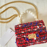 Front view of The Little Lady Tweed Mini Purse featuring textured tweed fabric, pearl top handle, and detachable gold chain for elegant wear.