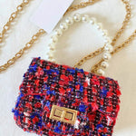 The Little Lady Tweed Mini Purse in red, blue, and black tweed with pearl handle and gold chain. Micro handbag ideal for chic, versatile styling.