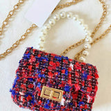 The Little Lady Tweed Mini Purse in red, blue, and black tweed with pearl handle and gold chain. Micro handbag ideal for chic, versatile styling.