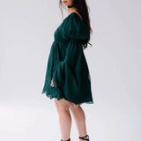 A woman wearing a green bell sleeve mini dress on a white background.