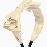Cream-colored bow headband with decorative bow and rhinestone accents for elegant gowns