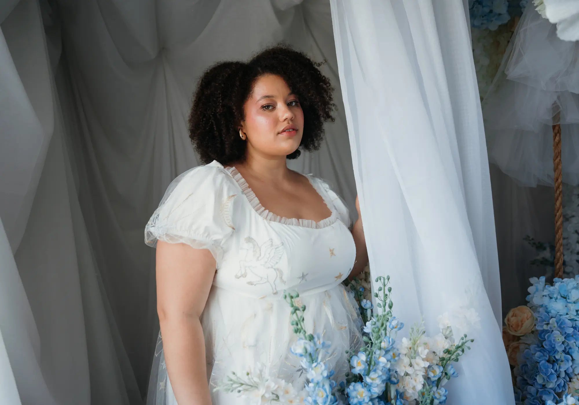 A model wearing the celestial veil dauphine lace gown in a bridgerton styled scene.