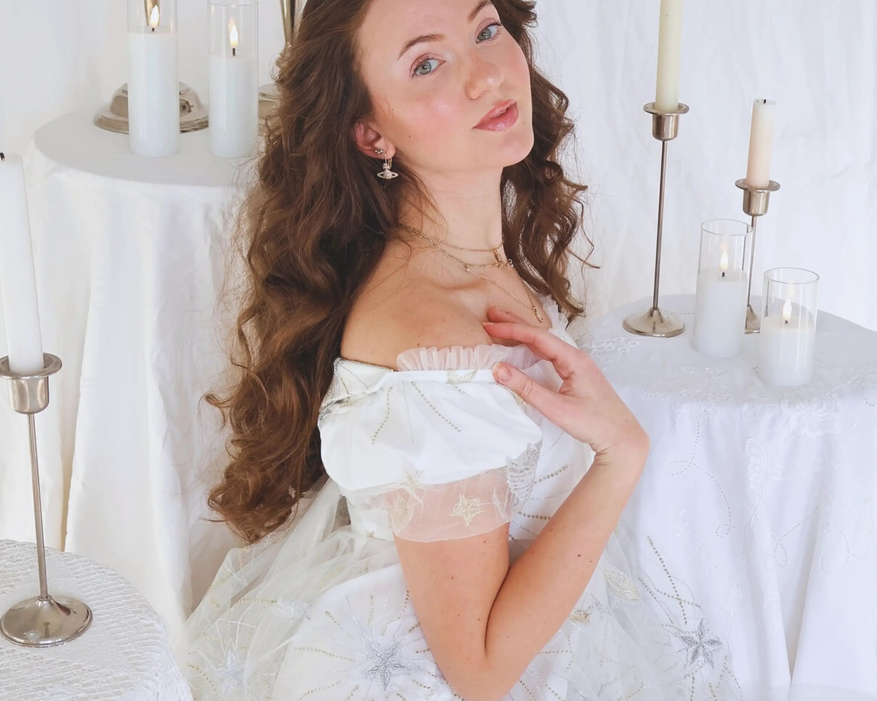 Influencer jmaclaren stuns in the celestial veil dress in a romantic setting surrounded by candles and linens. 