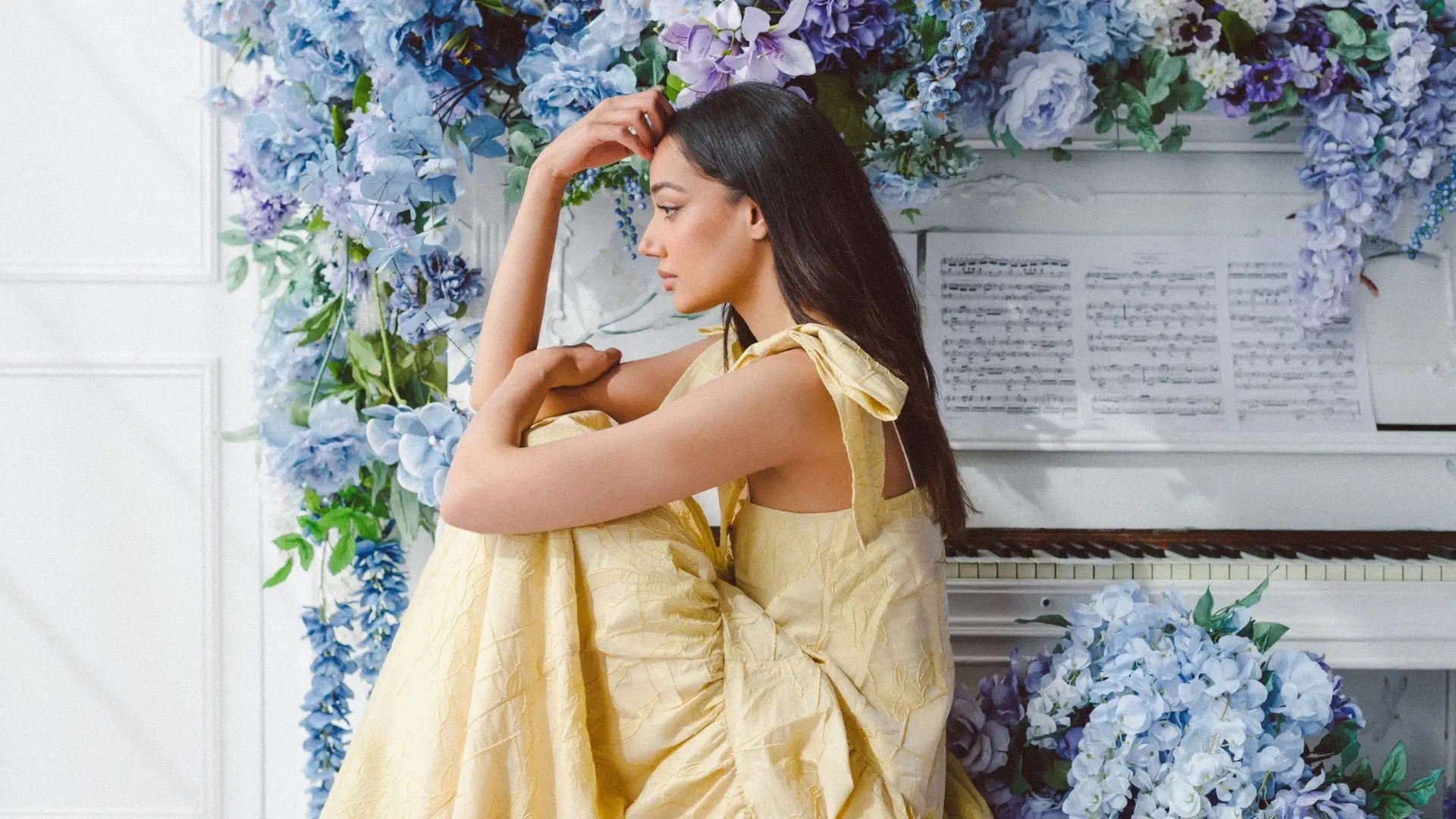 Woman in a flowing yellow dress poses against floral backdrop for Online Detective Shopper article.