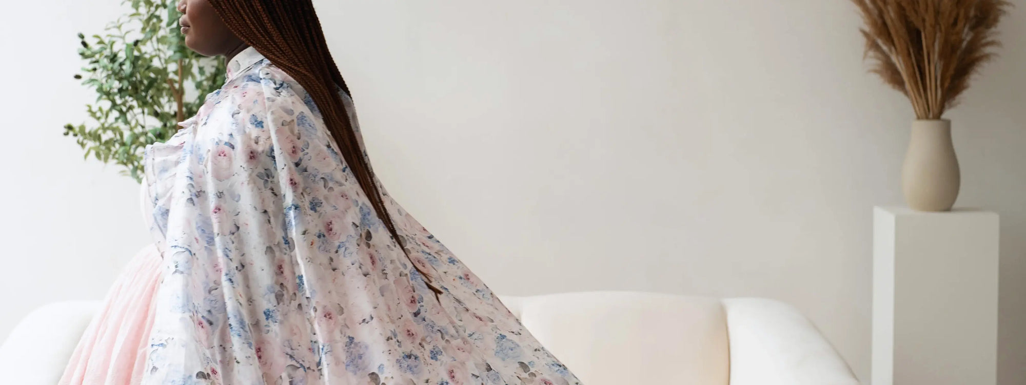 A woman wearing flowing floral designer dress and floor length cape in an elegant setting.