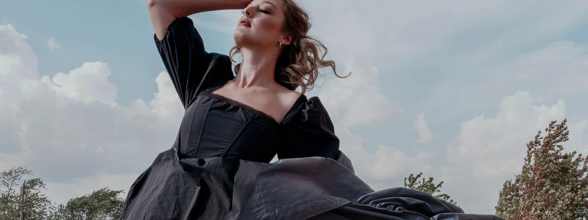 A woman wearing a black corset dress on a balcony