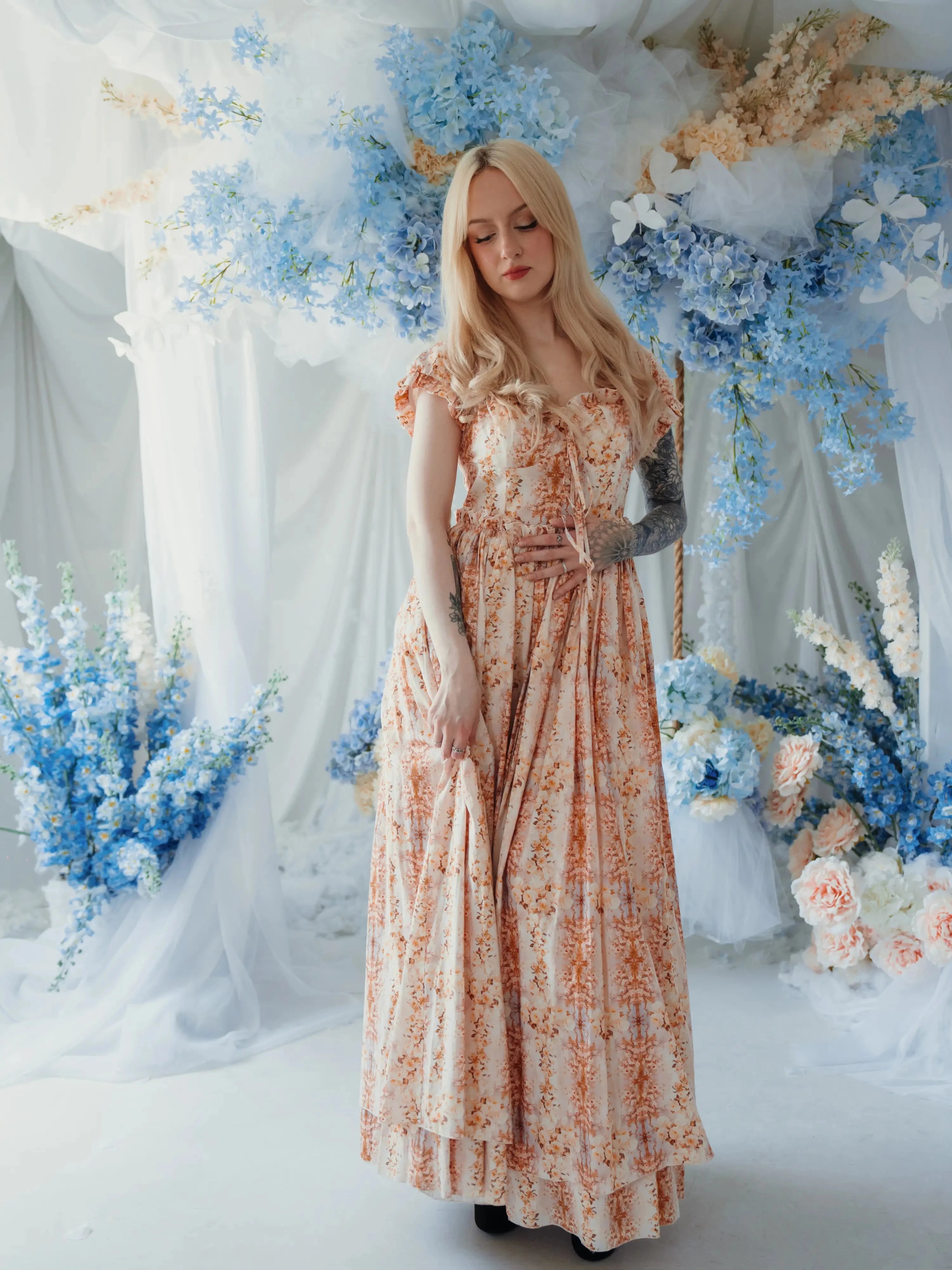 Twilight Bloom Meadow Gown styled in floral set with soft lighting, showcasing dreamy cotton fabric and puff sleeves.