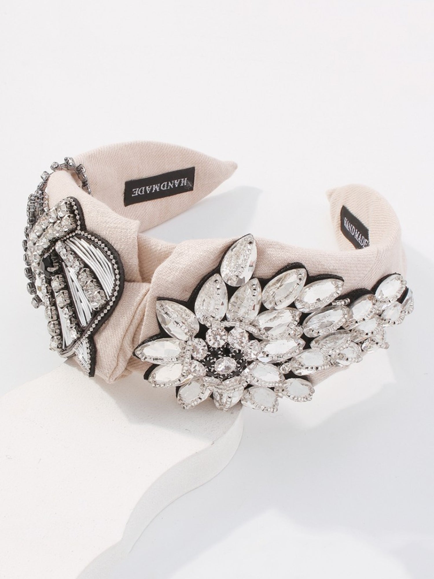 The Queenship Headband - The Queenship Headband is for all accessory collectors! This is a statement piece that has the finest handmade details. Made of a soft beige cotton, this headband has a crystal embellished crown with cascading crystal bow. On the