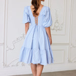 The Alice Blue Josephine Midi Dress, a dress designed with puff sleeves, corset laced back detail, and a ruffled hem.