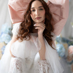 Close-up of Belladonna Lace Dress featuring lace texture and soft tulle, styled with oversized pink bow for whimsical bridal look.