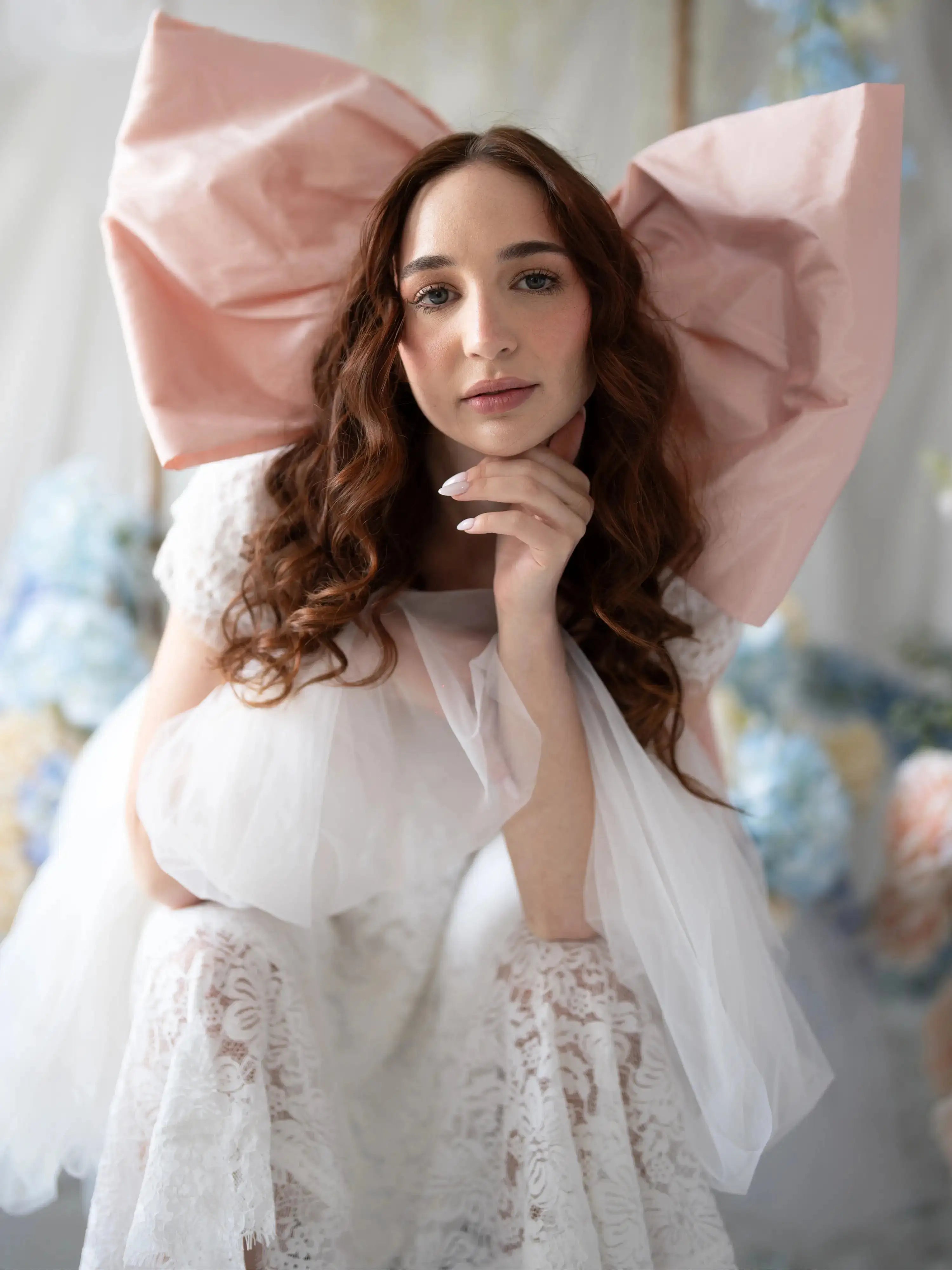 Close-up of Belladonna Lace Dress featuring lace texture and soft tulle, styled with oversized pink bow for whimsical bridal look.