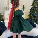 Dark green dress with bell sleeves, flowing skirt, and a giant holiday red flutter bow hair accessory