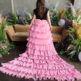 Voluminous pink Dahlia Ruffle Skirt with long train and snap closure buttons worn by woman surrounded by flowers for a fairytale scene.