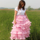 Pink multi-tiered Dahlia Ruffle Skirt with snap closure buttons paired with a white t-shirt, worn by a woman in a field for a fantasy look.