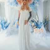 Dauphine Lace Gown bridal maxi dress with puff sleeves and empire waist, styled with oversized pink bow in a floral wedding setting.